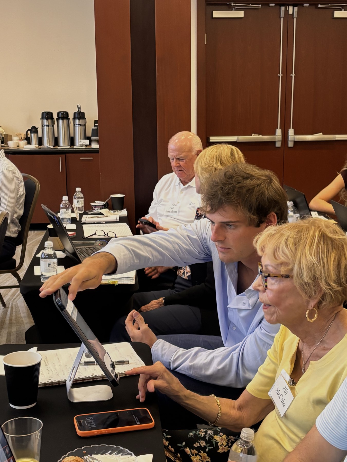 Tate helping a bank workshop attendee with her first prompts on a tablet