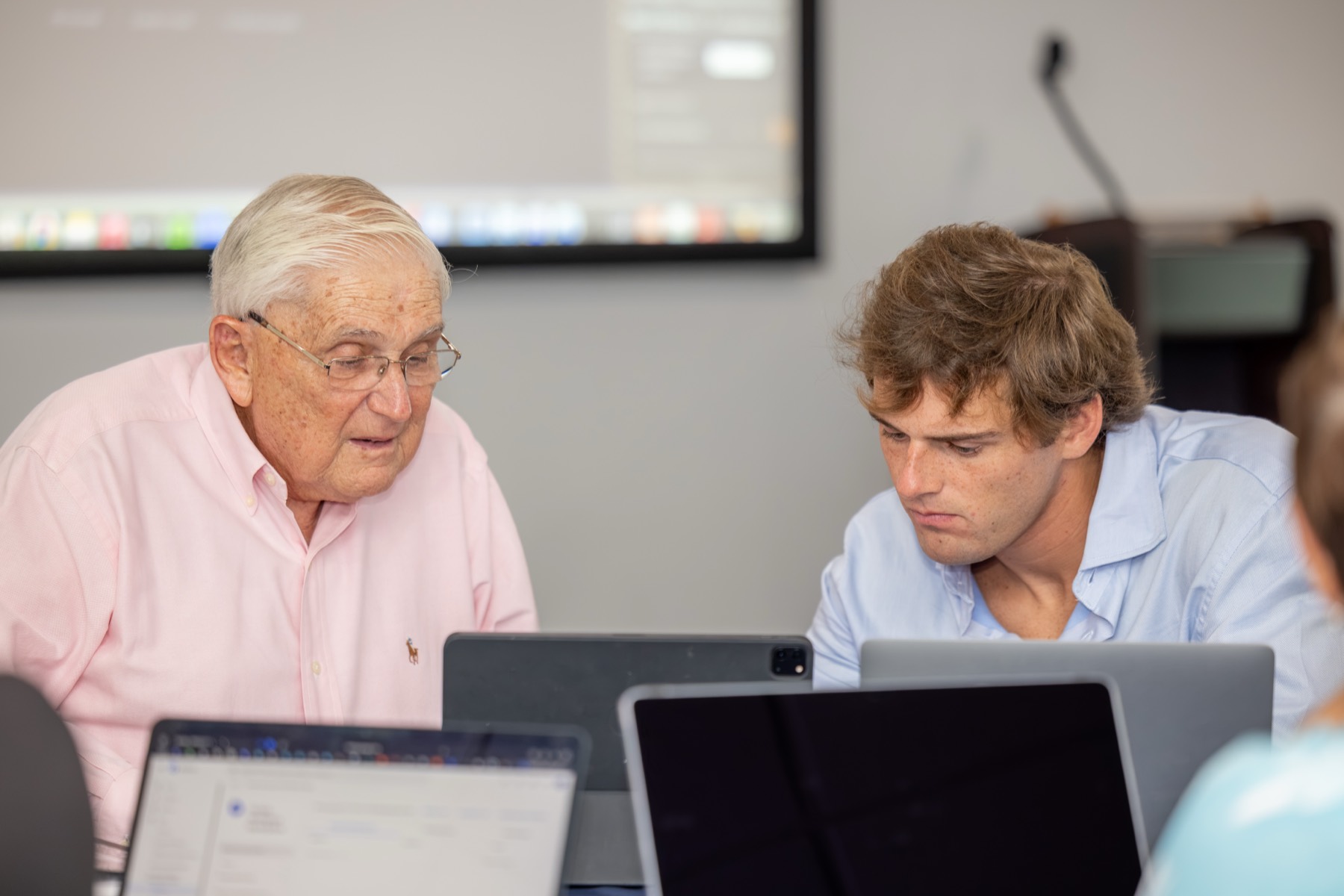 Tate helping a workshop attendee with Claude at a laptop